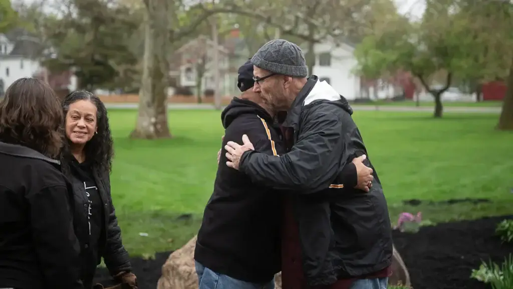 RAID members embrace at the memorial garden planting